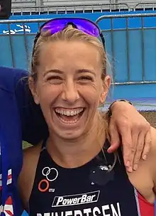 Sarah Reinersten wearing blue-tinted sunglasses on top of her head and smiling widely