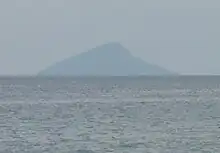 The island photographed from a great distance, which results in the image only revealing the island's outline.