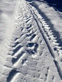 Compaction in about 5 centimetres (2 in) of snow left behind a snow tire, showing tread-snow interaction.