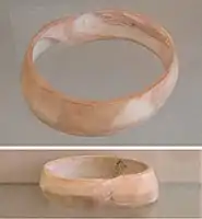 Indus bracelet, front and back, made of Pleuroploca trapezium or Turbinella pyrum imported to Susa in 2600–1700 BC. Found in the tell of the Susa acropolis. Louvre Museum, reference Sb 14473. This type of bracelet was manufactured in Mohenjo-daro, Lothal and Balakot. The back is engraved with an oblong chevron design which is typical of shell bangles of the Indus Civilization.