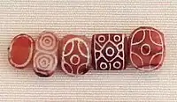 Indian carnelian beads with white design, etched in white with an alkali through a heat process, imported to Susa in 2600–1700 BC. Found in the tell of the Susa acropolis. Louvre Museum, reference Sb 17751. These beads are identical with beads found in the Indus Civilization site of Dholavira.