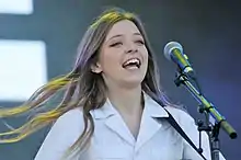 Woman in white clothing singing into a microphone