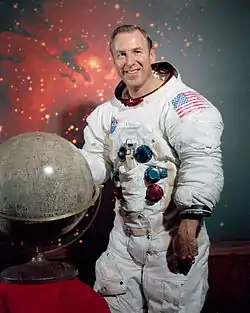 man in space suit, model of the moon in foreground