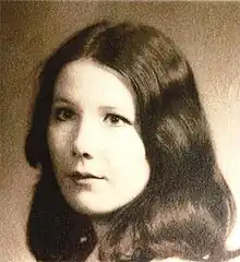 A sepia-toned image of a dark-haired young Caucasian woman looking slightly past the camera to the viewer's right