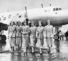 A black-and-white photograph of a Martin 2-0-2 aircraft with six cabin crew standing in front of the aircraft