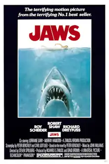 Movie poster shows a woman in the ocean swimming to the right. Below her is a large shark, and only its head and open mouth with teeth can be seen. Within the image is the film's title and above it in a surrounding black background is the phrase "The most terrifying motion picture from the terrifying No. 1 best seller." The bottom of the image details the starring actors and lists credits and the MPAA rating.