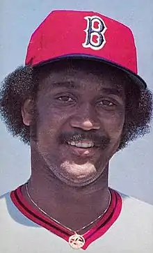 A man in a white baseball jersey and red cap