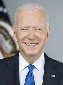  Biden standing with US flags behind him