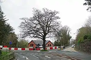 Three way road junction with bridge over river to left and building rooftops to centre behind road and lower down closer to river level