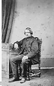 Man seated with right elbow on a desk