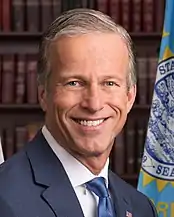 John Thune smiling in front of a South Dakota flag