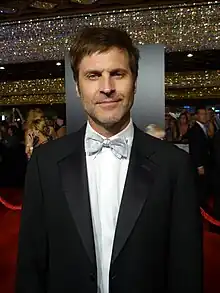 A man with dark hair, wearing a suit, including a bow tie.