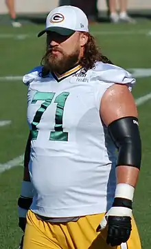 Sitton on the field wearing his uniform with a Packers hat on