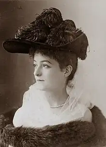 young woman in semu-profile, wearing a large and ornate hat