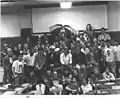 The Spring 1987 KMNR station photo in the old Mining Building.  First row: Cindy Walk, Jennifer Jones, Brent Jones, Vito Biundo (Ex-Station Manager), ?, Gene Hoeltge, ?, Steve Hendren, George Carini (Dr. Sunshine Show), ?, ?. Second Row:  Monster #?, ?, Bryan Adams, Jeff Brown, Jennifer Sommers, Jim Column, ?, ?, ?, ?. Third Row: Bald Dude, Kathy Dolsen (Former Personnel Director, Station Manager), ?, ?, Bob Linke, ?, James Haring, ?, ?, ?. Fourth Row: Scott Birdsong, Jeff Leith and Alletta Curtis (married), Eric Bussen, Dave Meriwether, ?, Mike Harvey (Ex-Station Manager), Rick Karbowski, ?, ?, ?, ?. Top Row: Doug Moyer, Kid with Had, ?, ?, Guy with Umbrella, Dean McDowell, Don Grahler, Greg Boice, Jim Calzone, Joe Heberlie, ?.