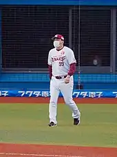 Man wearing a baseball uniform walking onto the field.