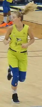 Hip high portrait of young blond woman wearing a yellow basketball uniform