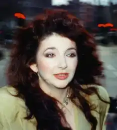 A zoomed in photograph of a Caucasian woman with dark red hair wearing a light yellow shirt.