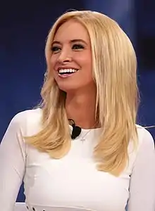 A 31-year-old woman smiling towards something to the right of the camera.