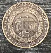 A bronze medal, bearing the legends, "BATTLE OF BENNINGTON" and "1777-1927" and 14 stars.  This surrounds a wreath with ribbons with the names of battle participants such as "ALLEN". Within the wreath is a building, and the inscription "FAY'S TAVERN".