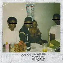 In an instant film photograph, three male adults, with one holding a baby, sitting in a room. The room has a table decorated with glasses, a bottle, and a decorated basket with a poster of a child and a person hanging in the wall. The eyes of the adults are covered with a black bar.