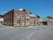 A two-story brick building extends from the foreground off to the right side of the frame. A road runs before it. The day is sunny and clear.