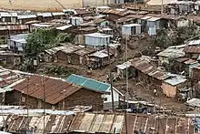 Small houses with corrugated metal roofs stand in ramshackle rows