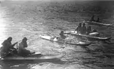 King Island residents in kayaks, about 1892. The kayaks are of the characteristic King Island style. Several carry more than one person or items on deck, and the paddlers are using single-blade paddles. Two-blade paddles were also used.