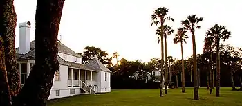 Photo of a sunset over a lawn featuring a large wooded area in the background