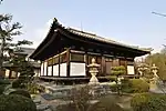 Wooden building with raised floor, white walls and a tile roof.