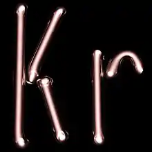 Illuminated white gas discharge tubes shaped as letters K and r