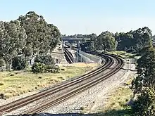 Long shot of a dual track freight railway to the left of a tunnel portal