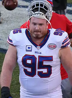 A light-skinned man wearing a white football jersey