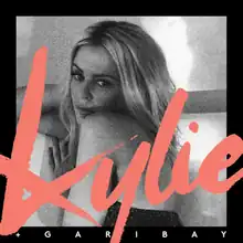 A black and white image of Kylie Minogue, with a black frame and the word "Kylie + Garibay" written on the bottom half