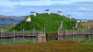 Grass-covered house with wooden chimneys.