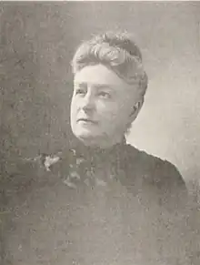 B&W portrait photo of an old woman with her hair in an up-do, wearing a dark blouse.