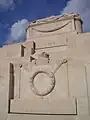 The memorial's sarcophagus, crown and wreath carvings, and the English inscription.