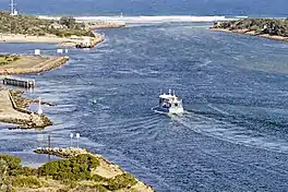 A boat sailing through the entrance to Grippsland Lakes