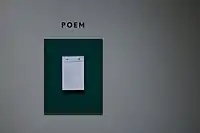 Paper hanging on a white wall with "Poem" written above it