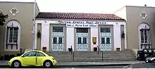 The entrance of a post office. There are several cars in front of it.