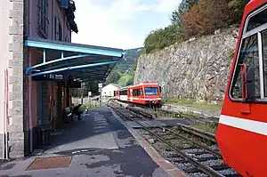 White-and-trains on double-track railway line next to two-story station building