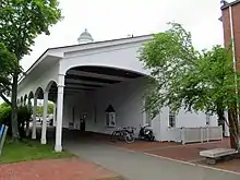 A paved bike path passing under an open but roofed section of a former train station