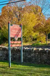 A rock wall and trees behind a large signpost