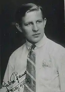 A portrait of a short-haired trans man in a white shirt and tie.