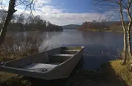 A rowing boat on an inlet ova lake surrounded by trees