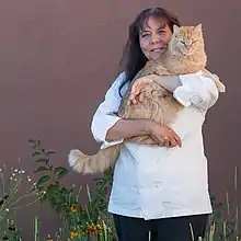 Woman in chef's whites holding a large cat