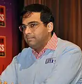 A photograph of a man playing chess with blue sweater.