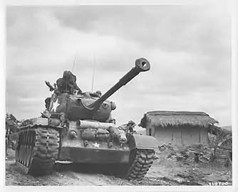 M46 Patton tank and crew passing through the village of Kumko, Korea, in September 1950.