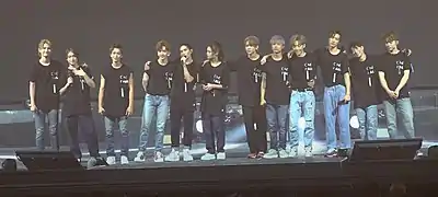 Front view of Mirror members at their concert wearing black t-shirts and jeans