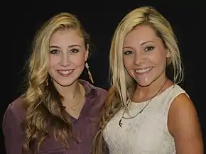 Two young blonde-haired women smiling broadly